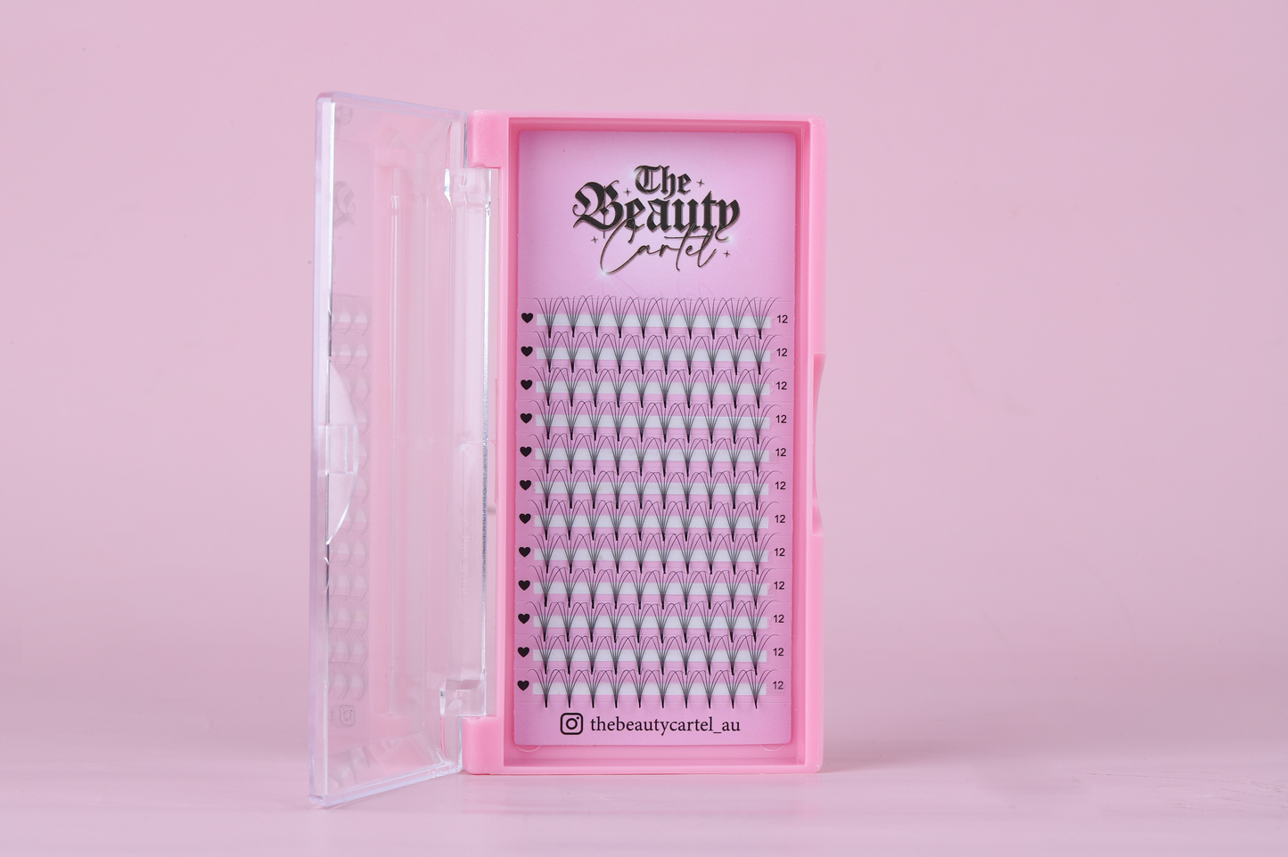 A pink lash tray with clear dividers, labeled 'The Beauty Cartel', containing various sizes of false eyelashes.